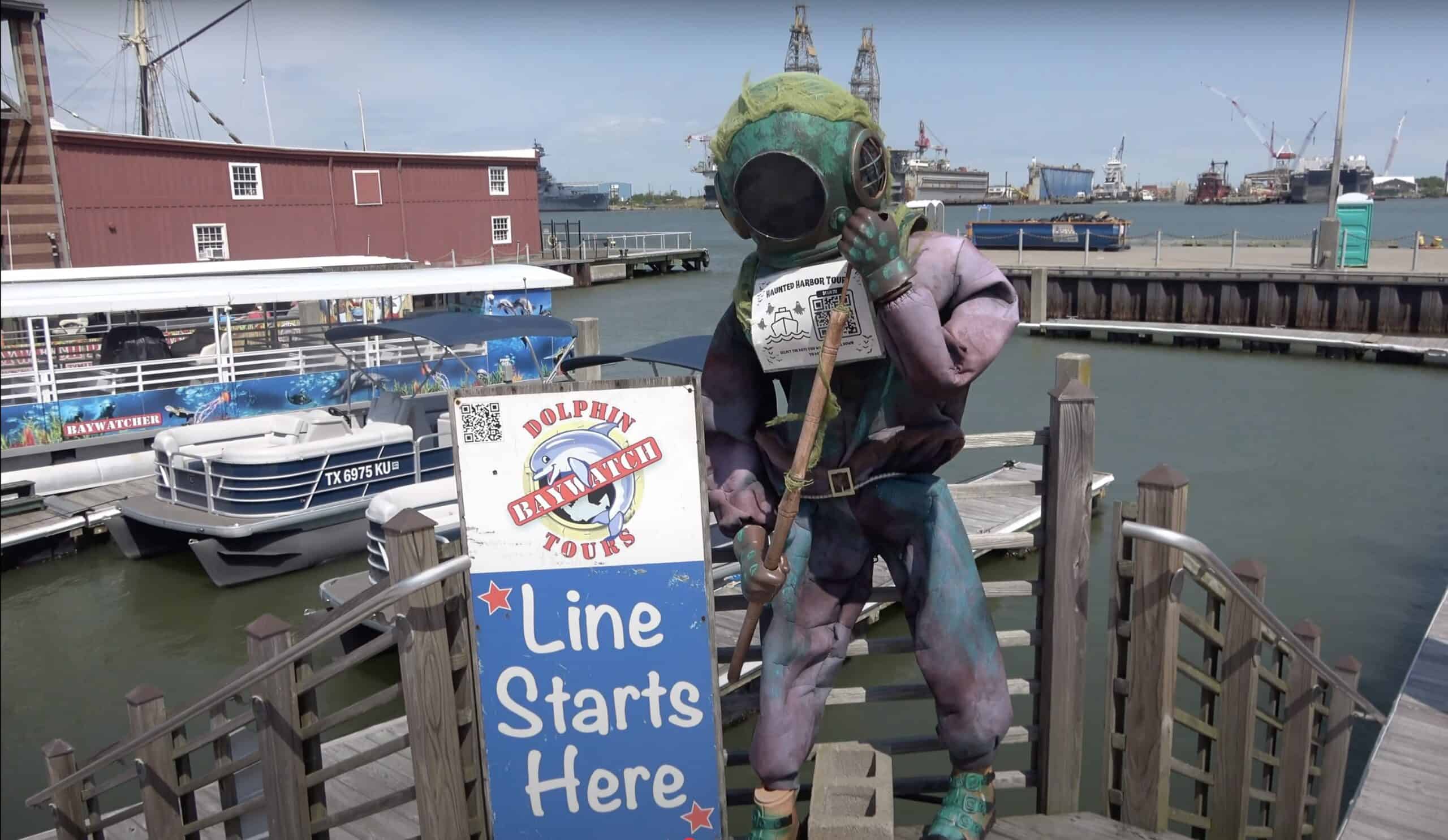 Pier 21 Galveston Dolphin Baywatch Tours entrance with deep-sea diver statue, tour boats, and harbor views — popular spot for Galveston dolphin tours and cruise visitors