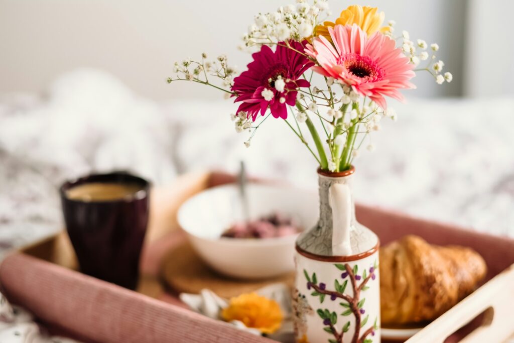 assorted flowers in a vase with breakfast on a tray