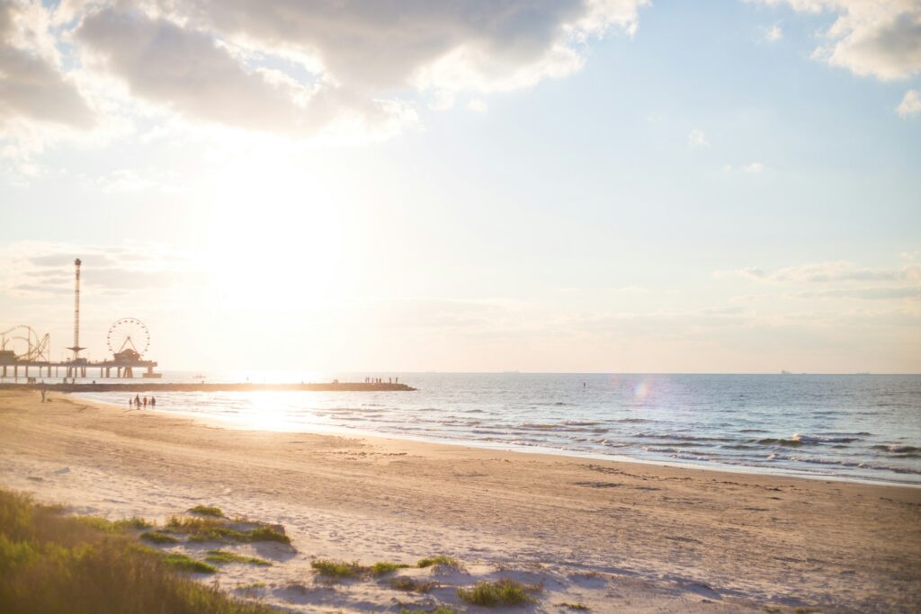 Beautiful sunset view of Galveston Beach with Pleasure Pier amusement park in the distance — popular Gulf Coast destination for cruise passengers and Texas beach vacations