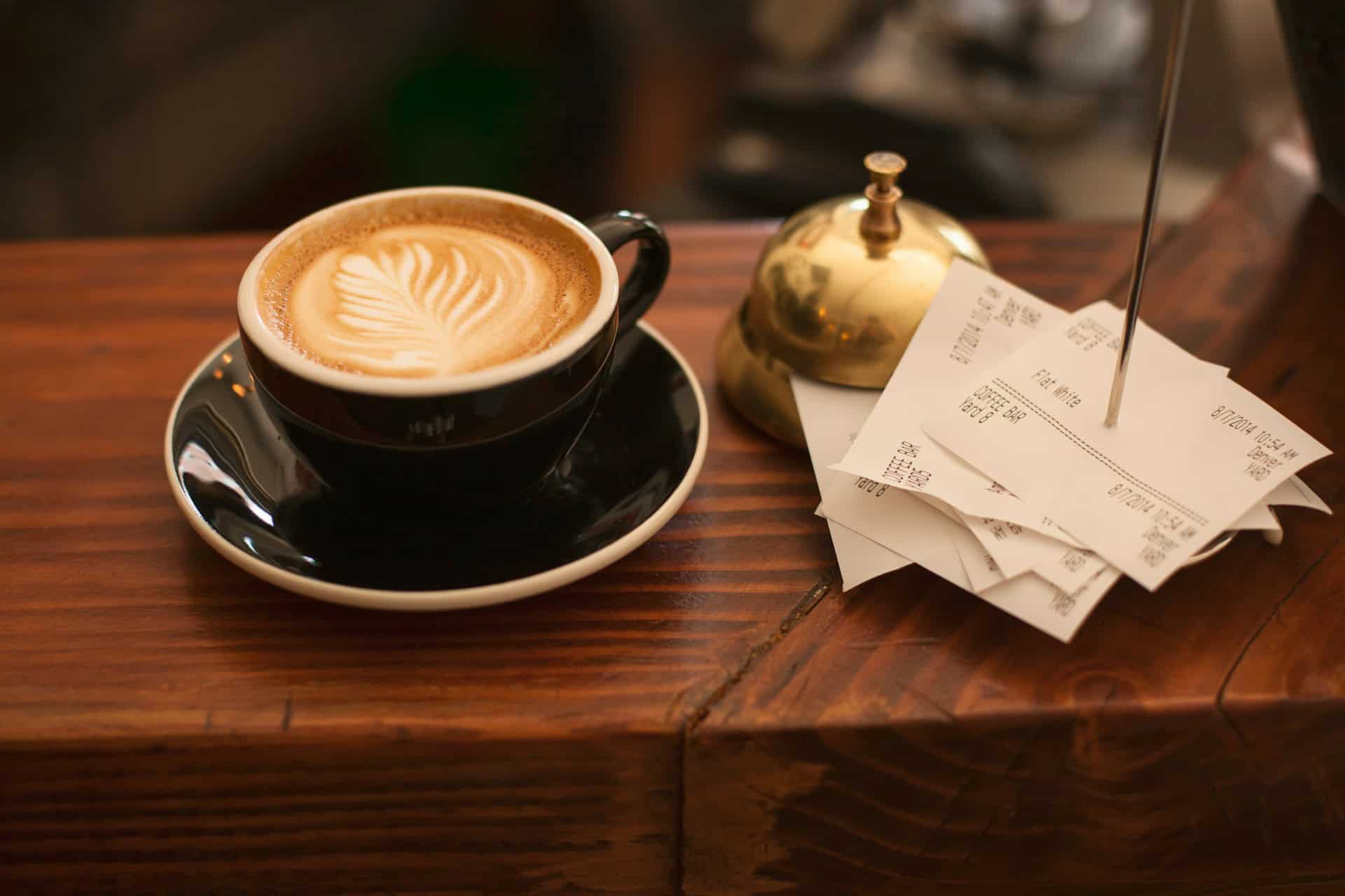 Front desk hotel bell, cup of coffee, and receipts