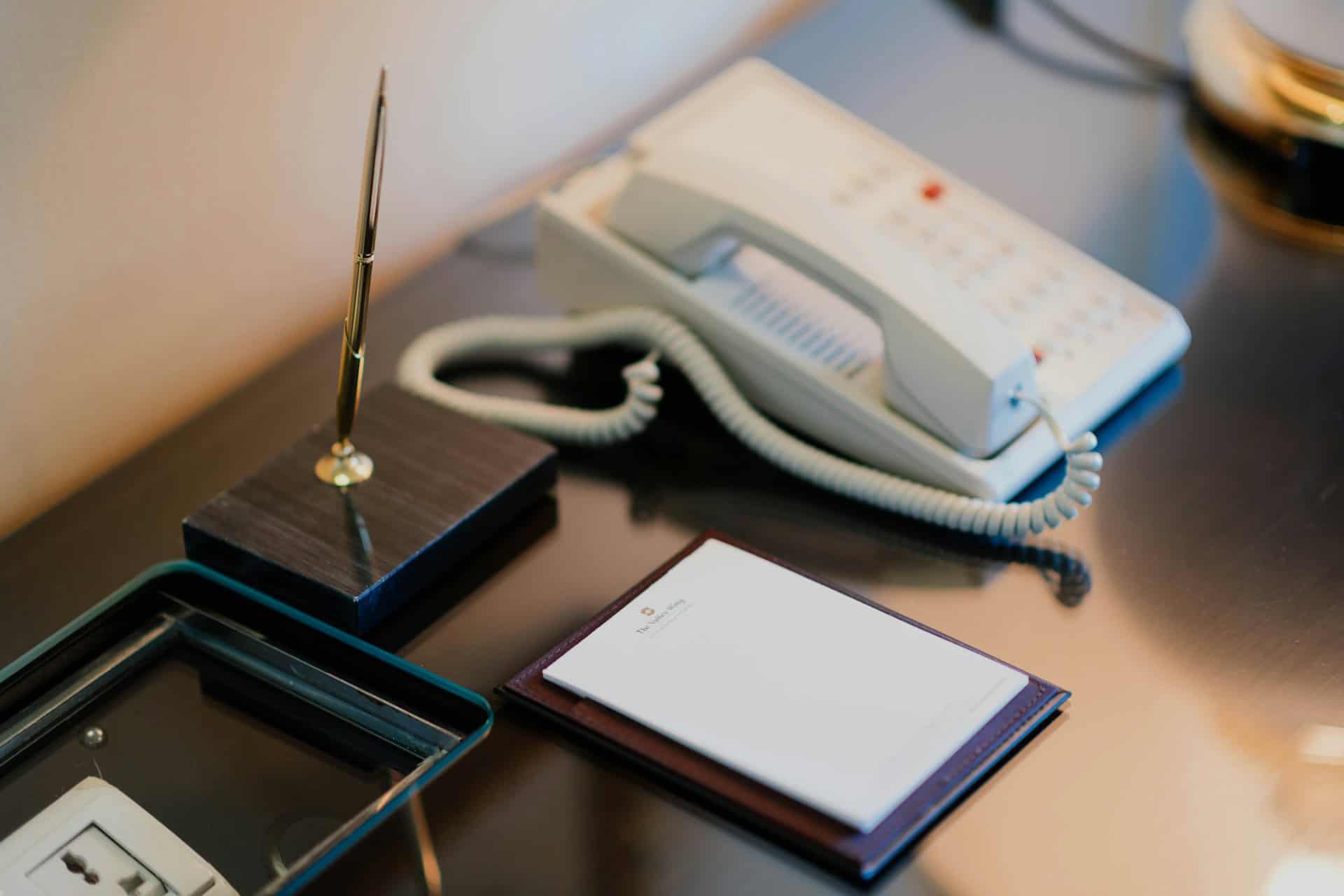 Hotel desk phone, notepad, and pen